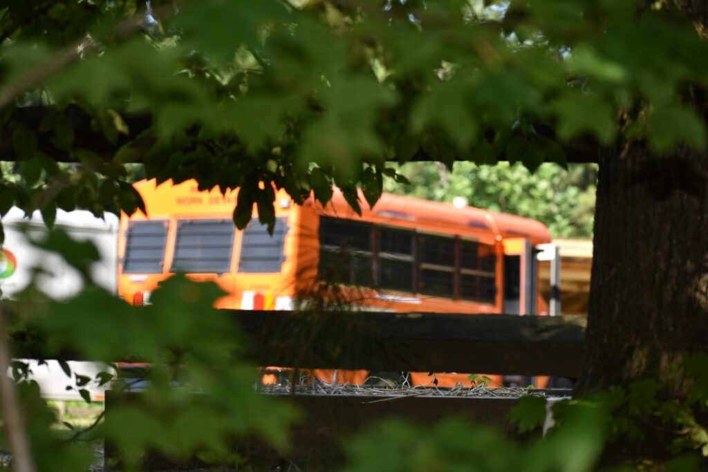 An orange Gwinnett County Corrections mini bus, used to transport prisoners, is seen through the foliage of a tree at the Gwinnett Environmental and Heritage Center.